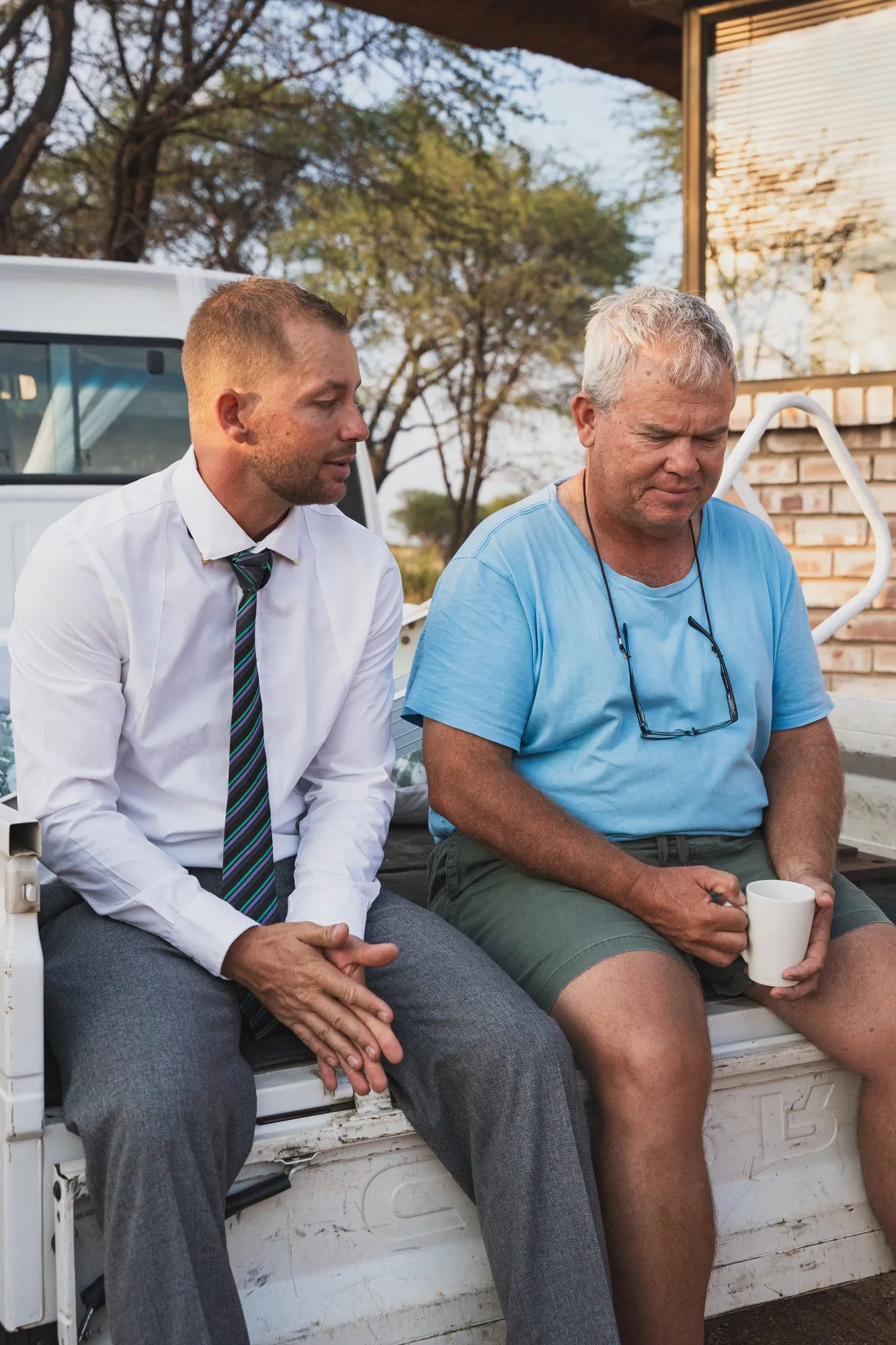 The groom sharing a joke with a guest on the back of a bakkie