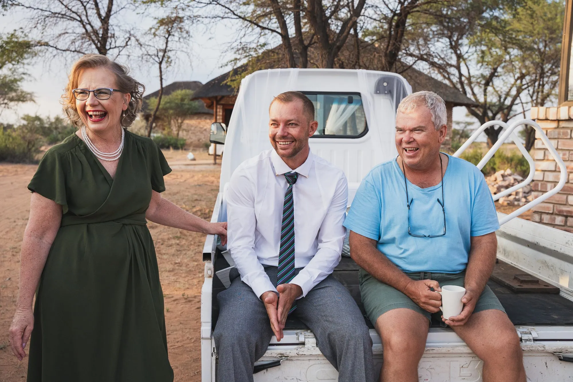 Three guests laughing together on the back of a bakkie