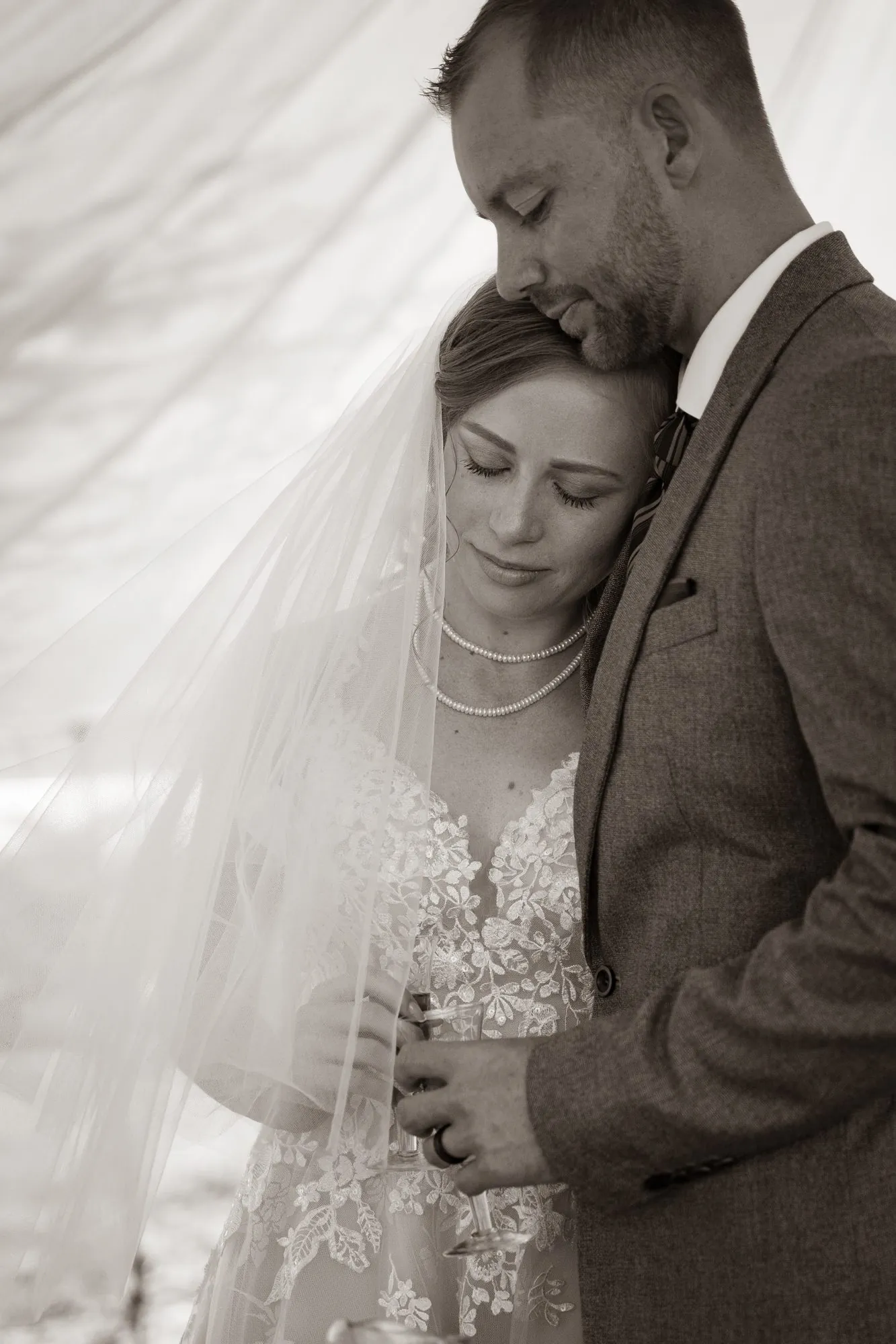A bride and groom held close beneath the veil
