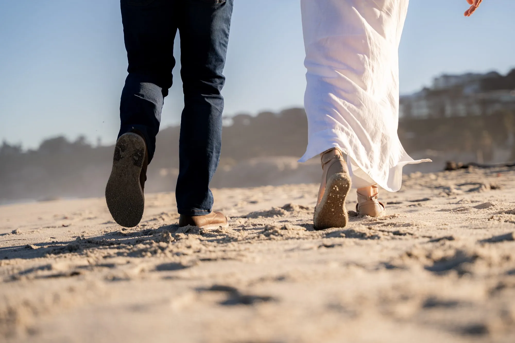 A couple close together on the beach at sunset