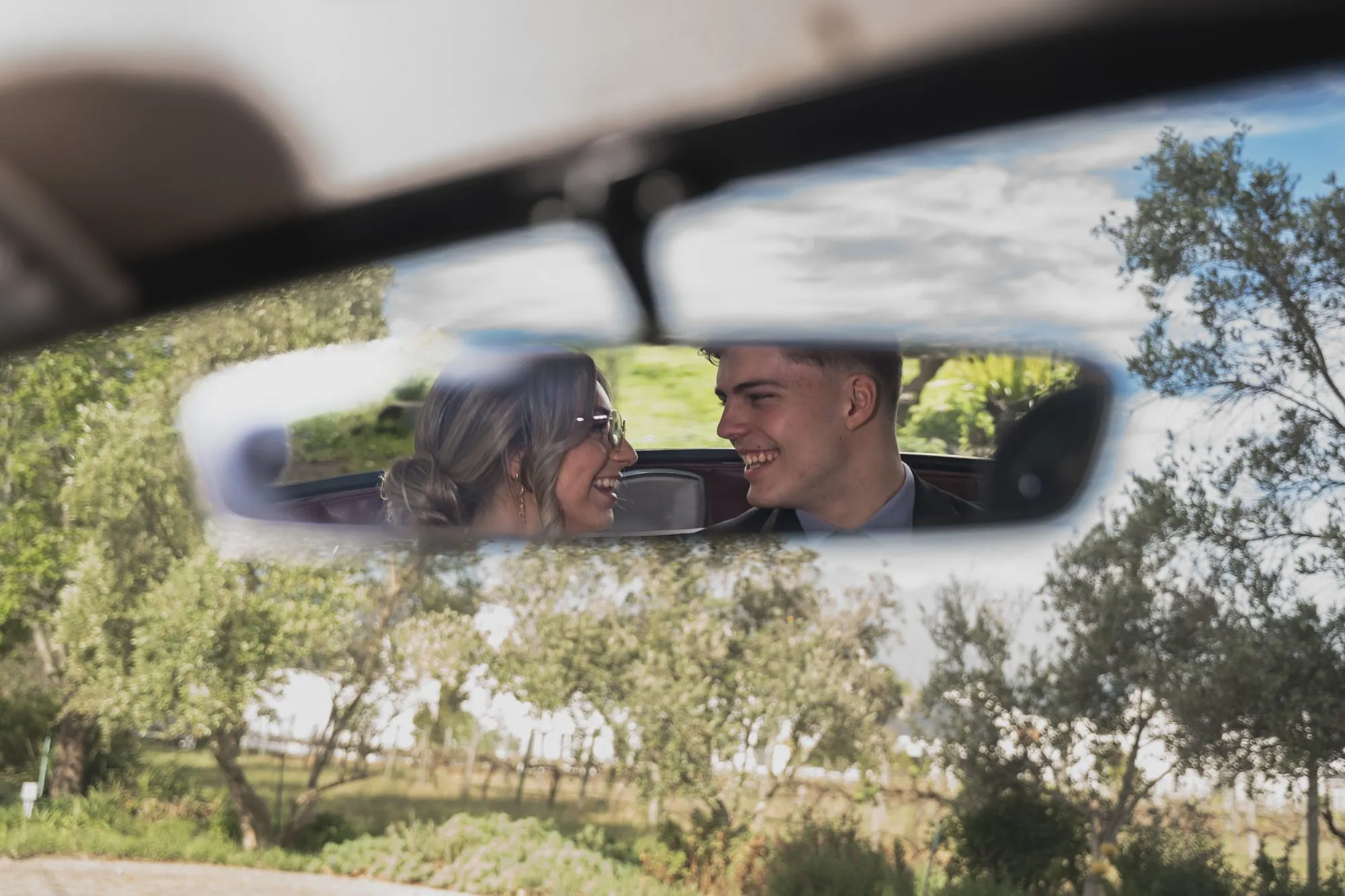 Matric dance couple in the rear-view mirror of a classic car